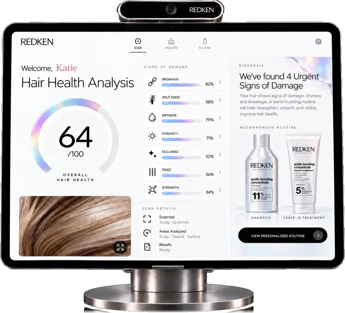 The Redken Hair Health Scan station: a camera bar above a tablet on a brushed-steel stand, its screen reading Hair Health Analysis with an overall score of 64 out of 100, seven signs of damage scored beside it, and a recommended Acidic Bonding Concentrate routine on the right.